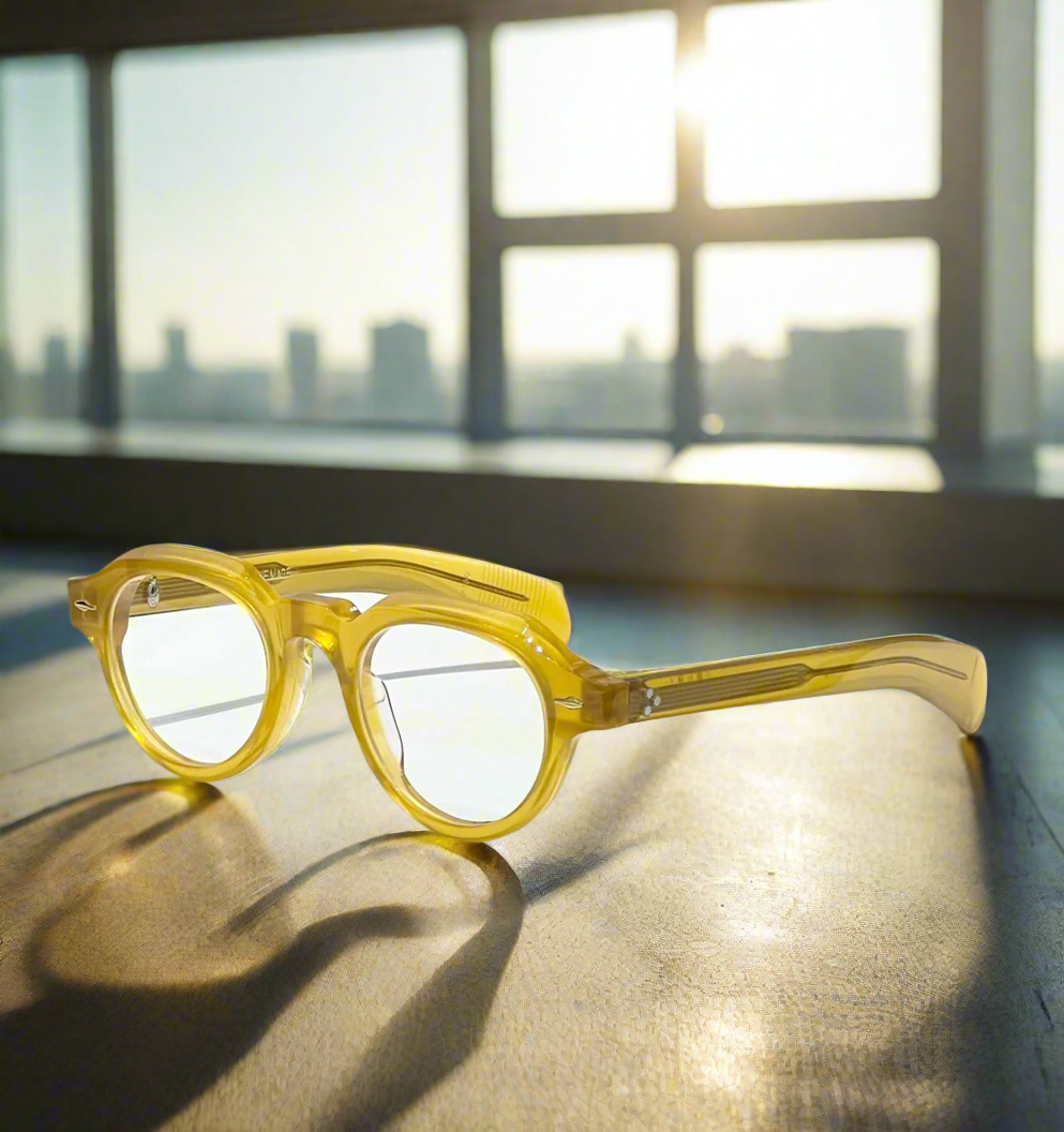 Yellow eyeglasses on a marble surface with decorative elements in the background