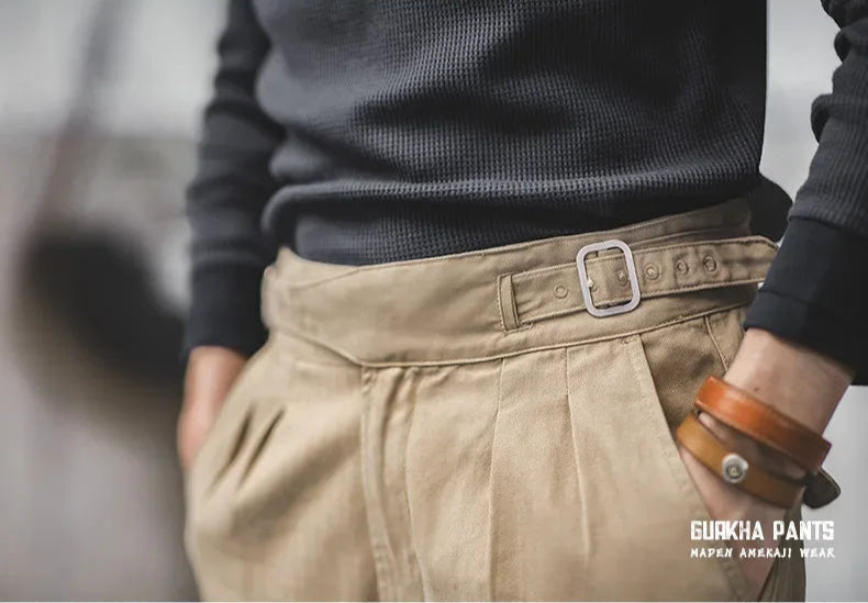 Close-up of a person wearing a dark sweater and beige pants with a visible brand logo.
