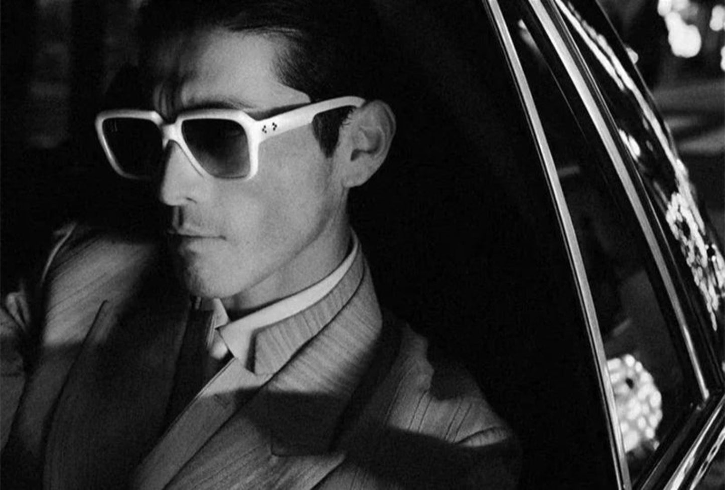 Person wearing sunglasses sitting in a car.