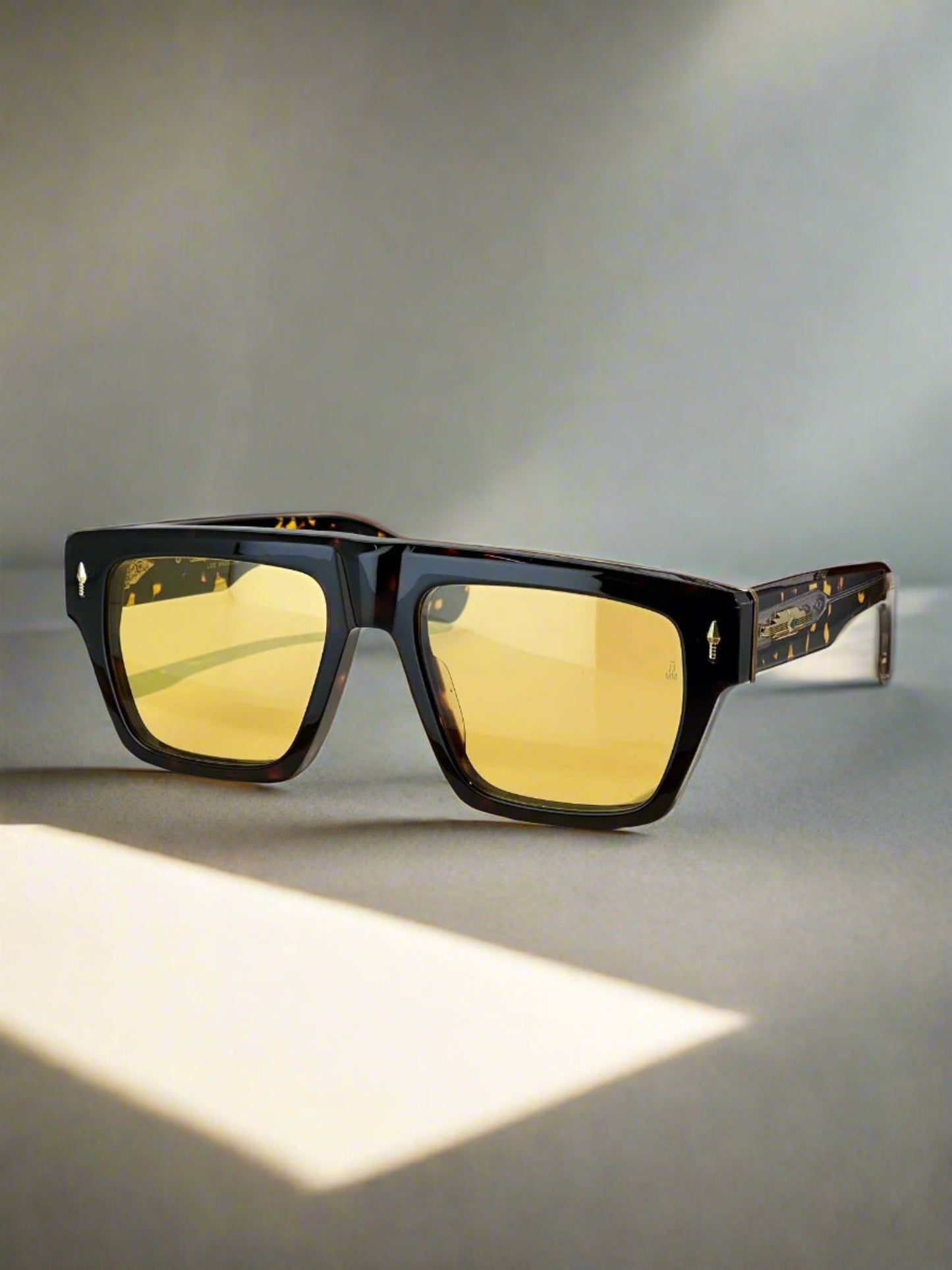 Sunglasses with gold lenses on a white surface next to a brown box with 'Louis Vuitton' branding.