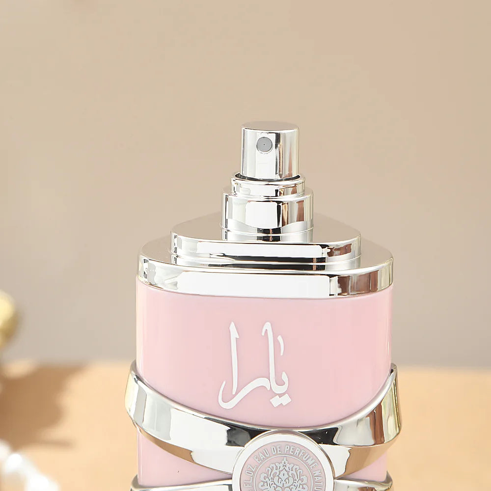 Pink perfume bottle with silver cap on a beige background