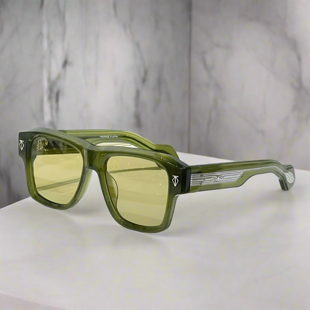 Green sunglasses with yellow-tinted lenses on a wooden surface with a white background
