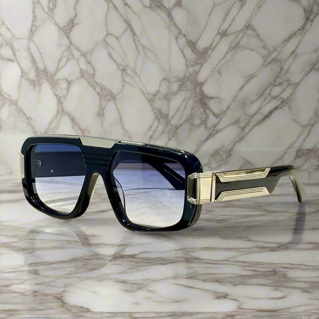 Sunglasses with black and gold frame on a wooden surface, with 'ABALMAY' branding.