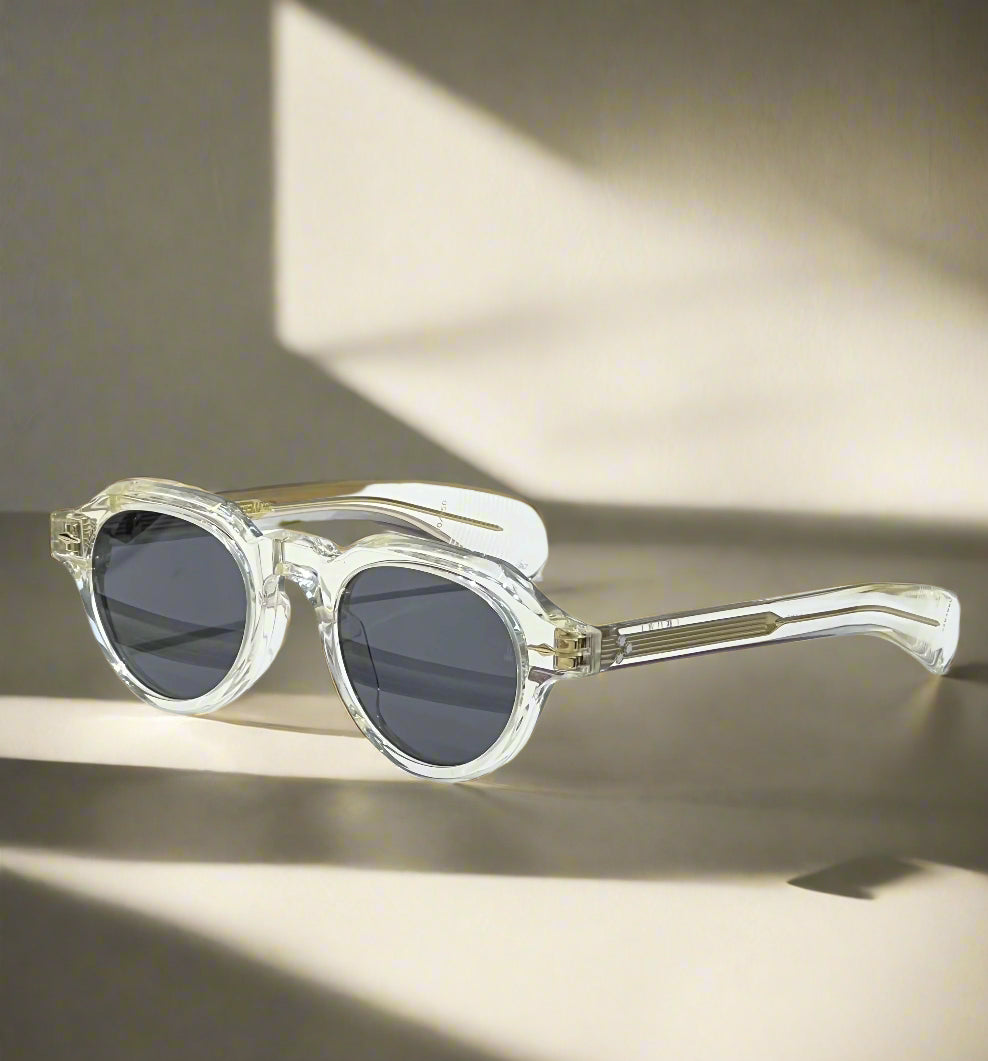 Clear sunglasses on a reflective surface with a maroon box in the background
