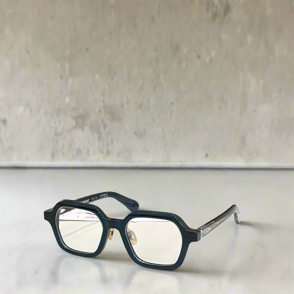 Blue eyeglasses with a red and gold box on a light background