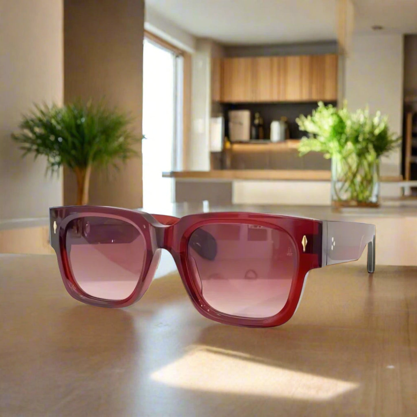Red sunglasses with a gold accent on a white surface