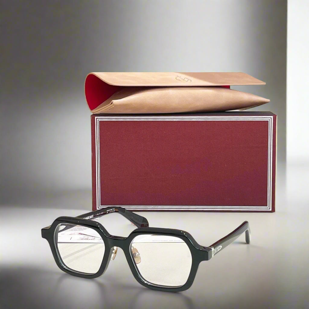 Black eyeglasses on a white surface with a red and beige box in the background