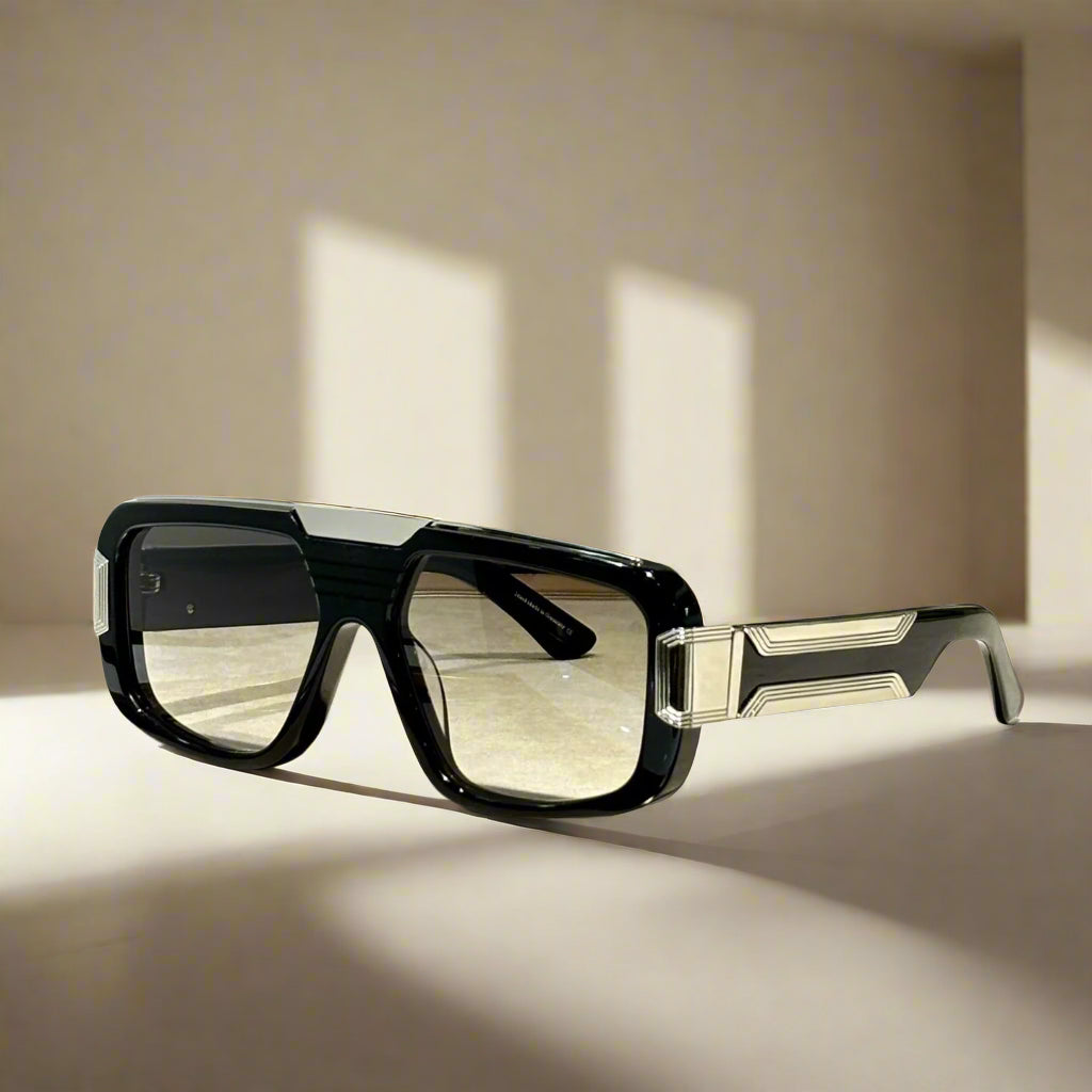 Black sunglasses on a wooden surface with a white background, featuring the brand 'ABALMAY'.