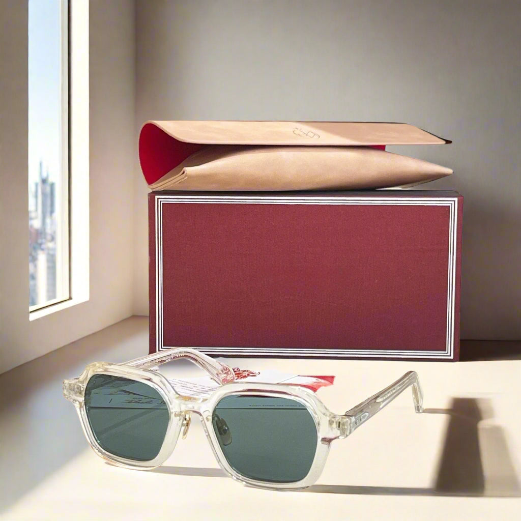 Sunglasses with a red box and beige pouch on a light surface