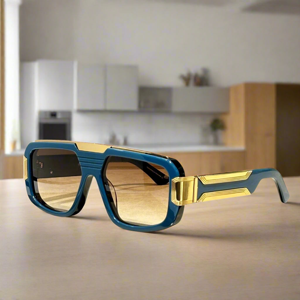Blue and gold sunglasses on a wooden surface with 'ABALMAY' branding.
