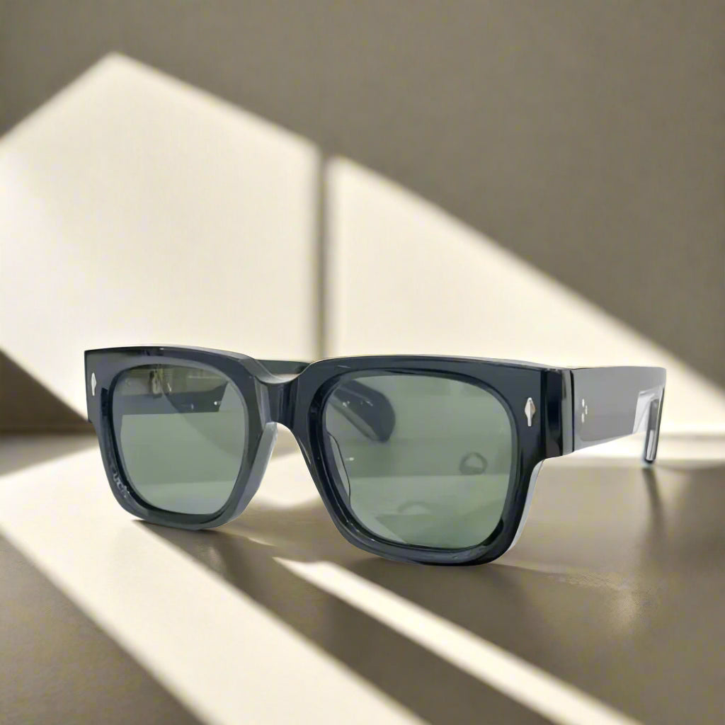 Black sunglasses with green lenses on a white surface