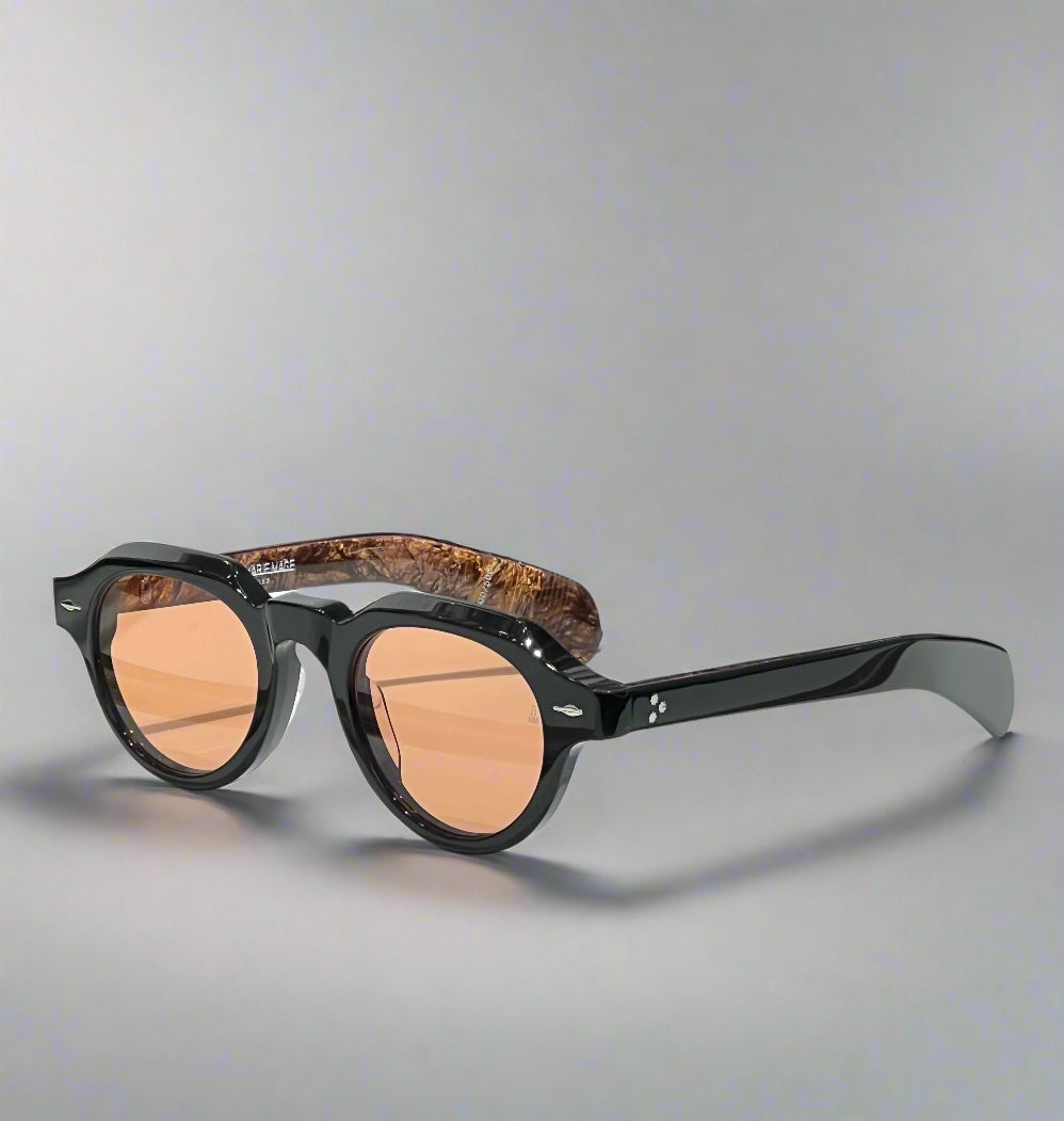 Sunglasses with tortoiseshell frame and brown lenses on a white surface with a branded box in the background.