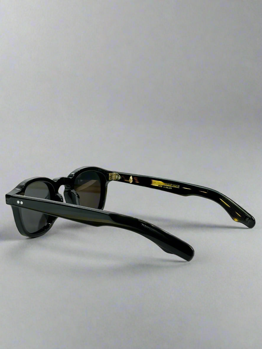 Black sunglasses on a white surface with a green box in the background