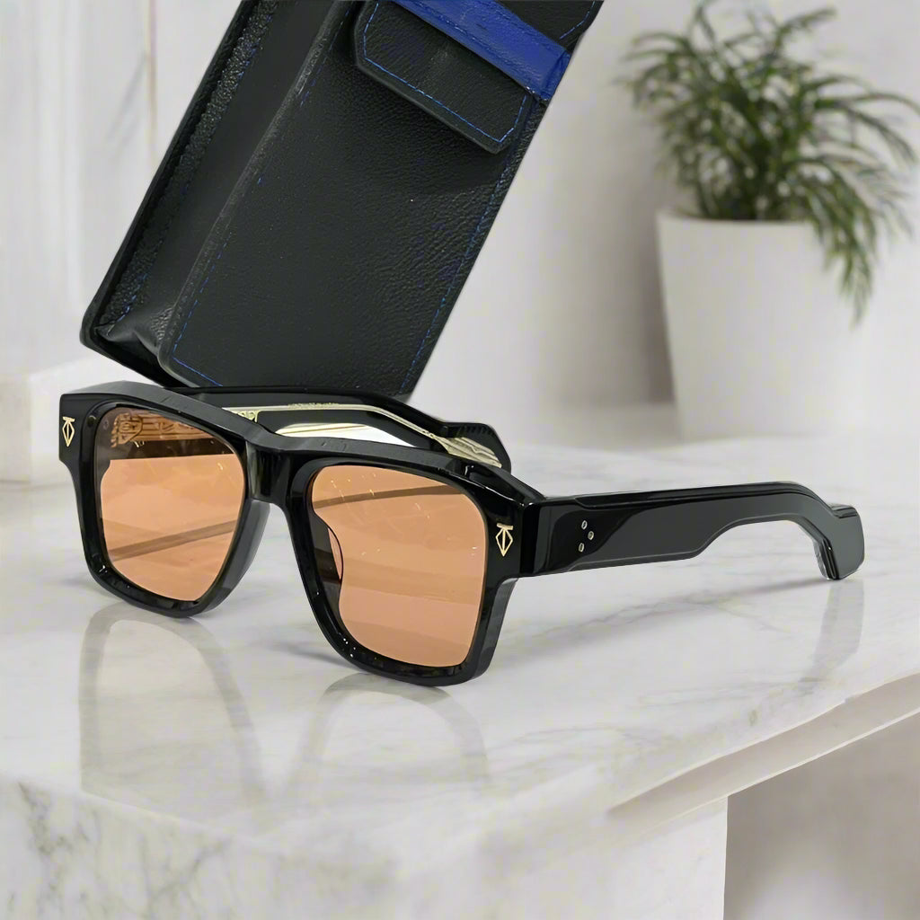 Sunglasses with black frame and brown lenses on a white surface with a black case in the background.