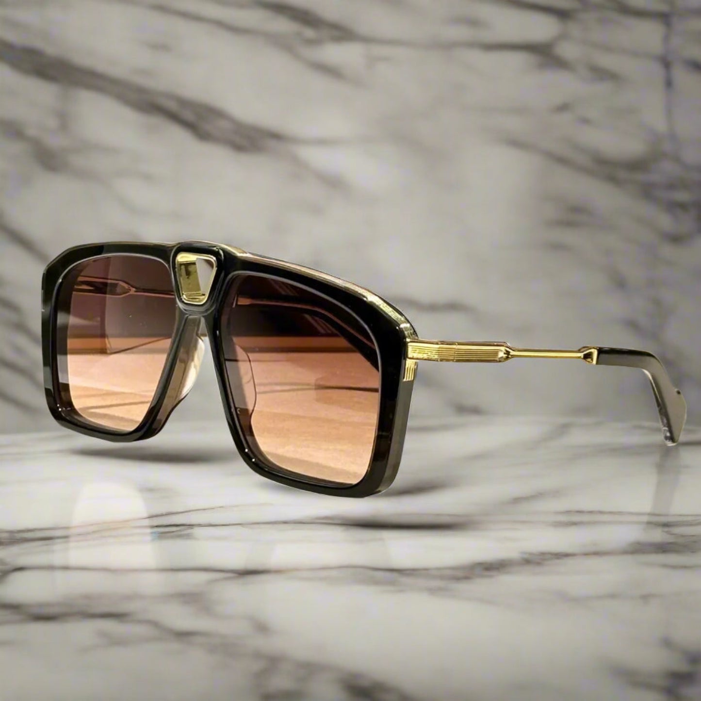 Sunglasses with gold frame and brown lenses on a wooden surface.