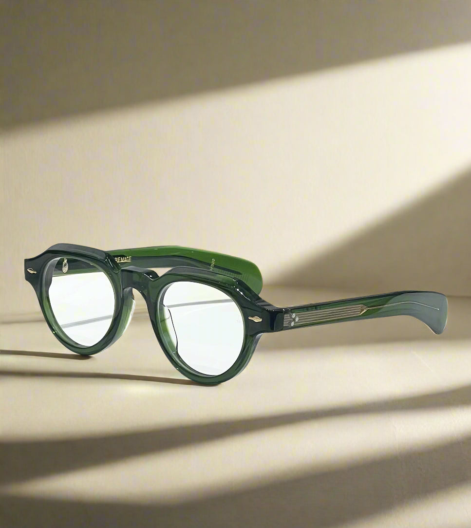 Green eyeglasses on a reflective surface with a branded box in the background