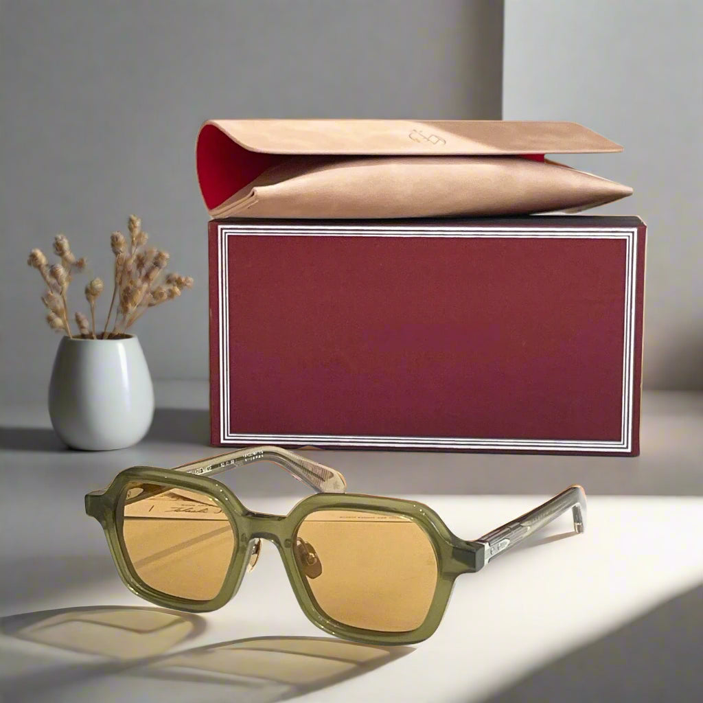 Green sunglasses with a red box on a white surface