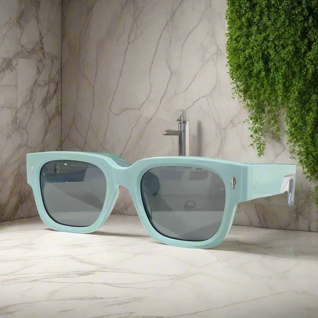 Light blue sunglasses with dark lenses on a white surface
