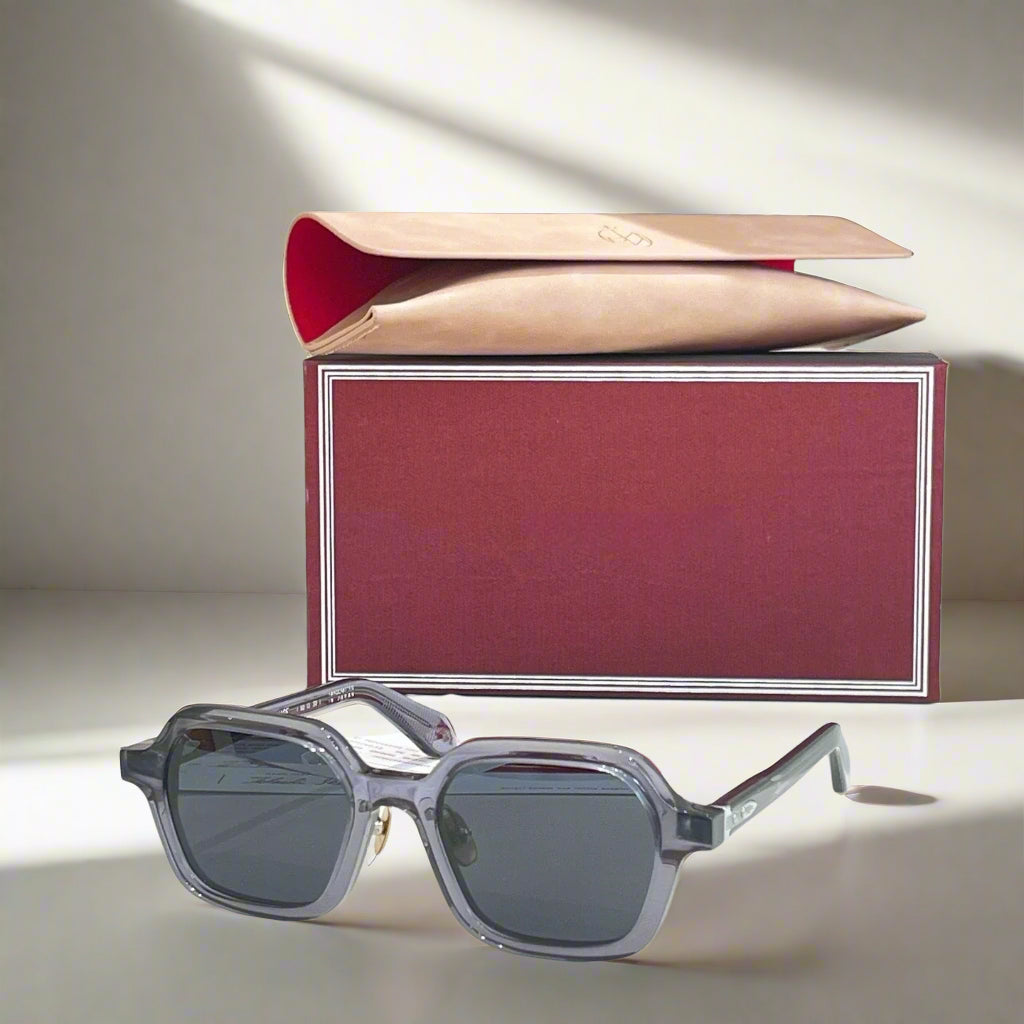 Gray sunglasses with a red and beige box on a light surface