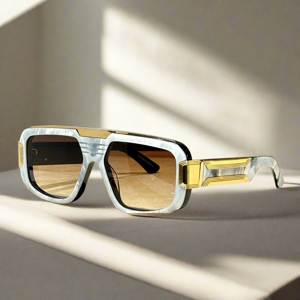 Sunglasses with gold accents on a wooden surface, with 'ABALMAY' branding.