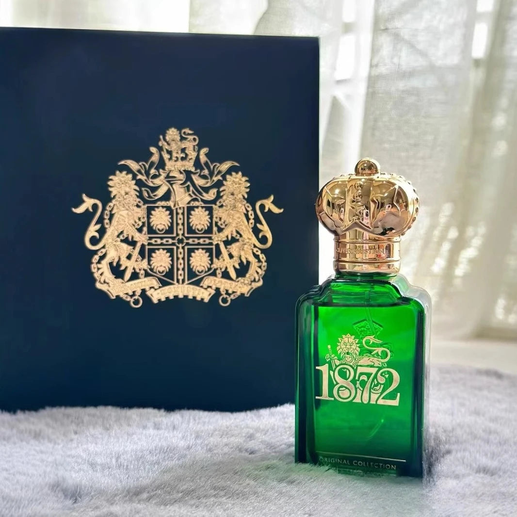 Green perfume bottle with gold cap and '1872' branding next to a blue box with a gold emblem.