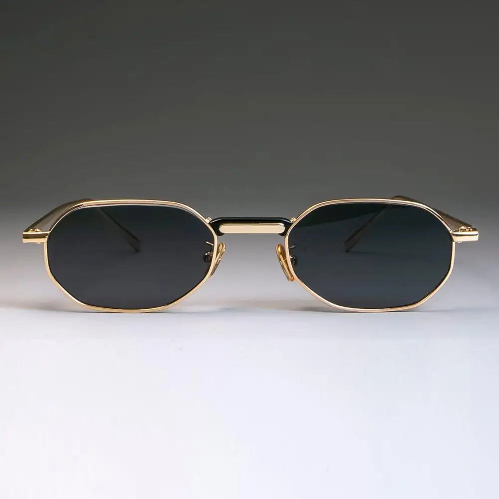 Gold-framed sunglasses with black lenses on a gradient gray background