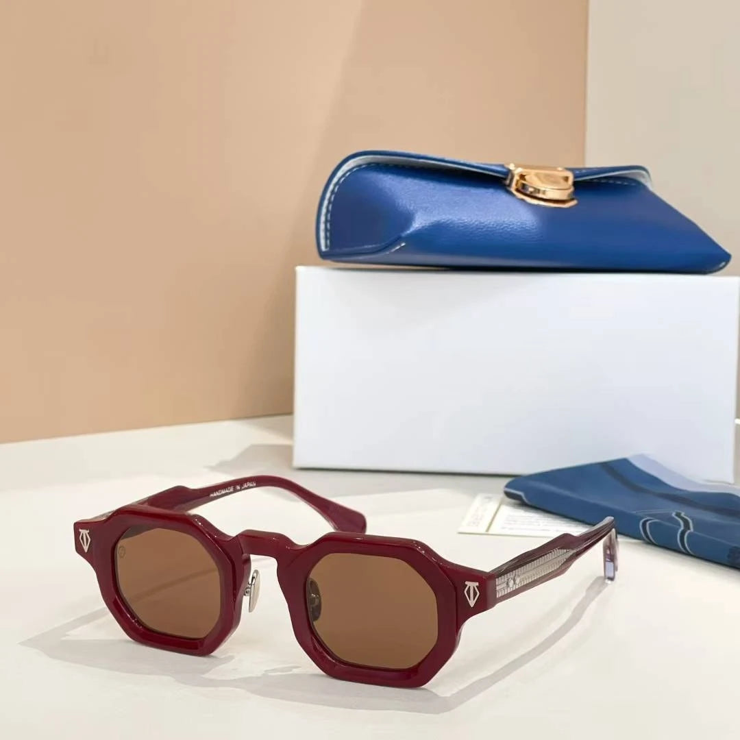 Red sunglasses with a blue clutch and white box on a beige background