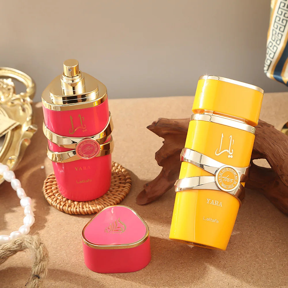 Two perfume bottles, one pink and one yellow, on a textured surface with decorative elements.