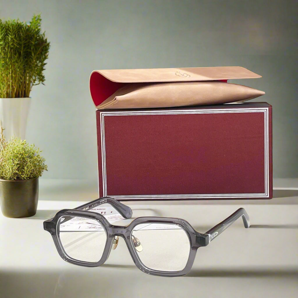 Gray eyeglasses on a white surface with a red and gold box in the background