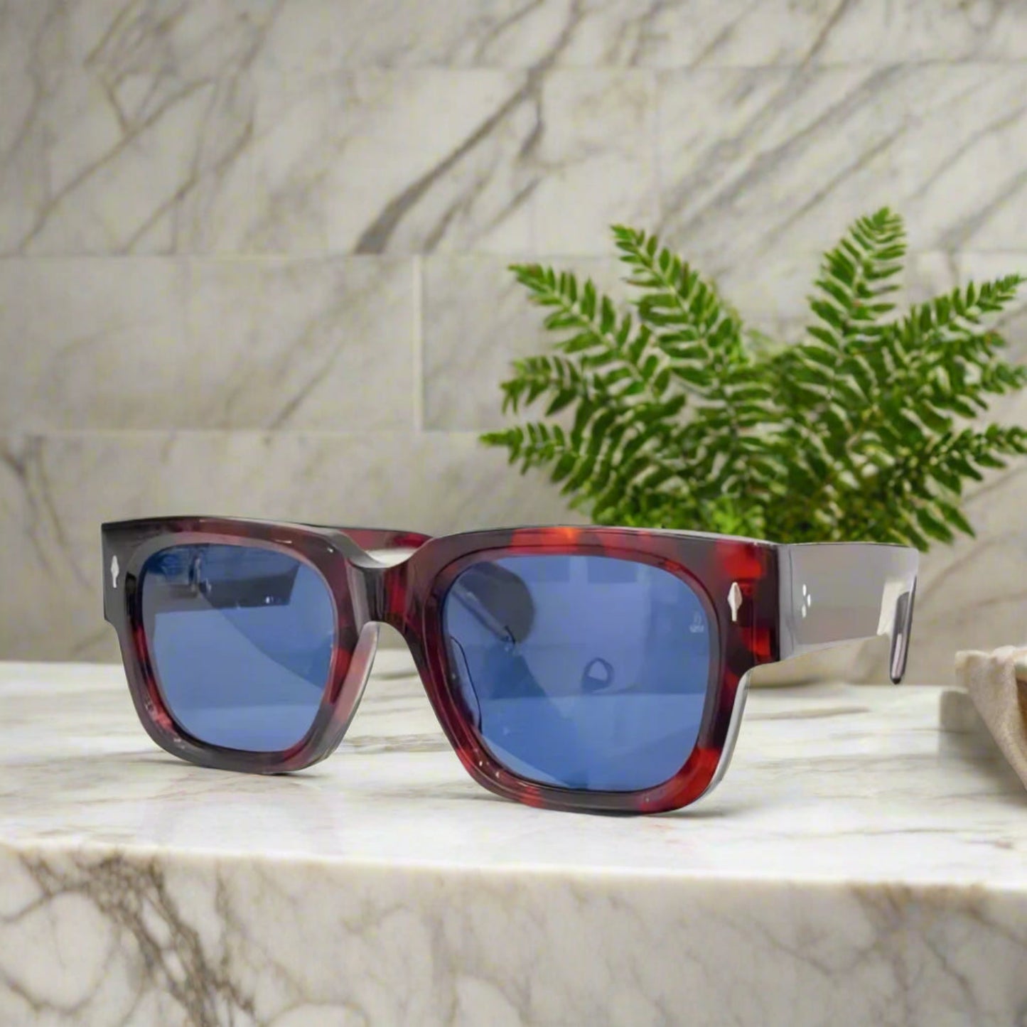 Sunglasses with red tortoiseshell frame and blue lenses on a white background