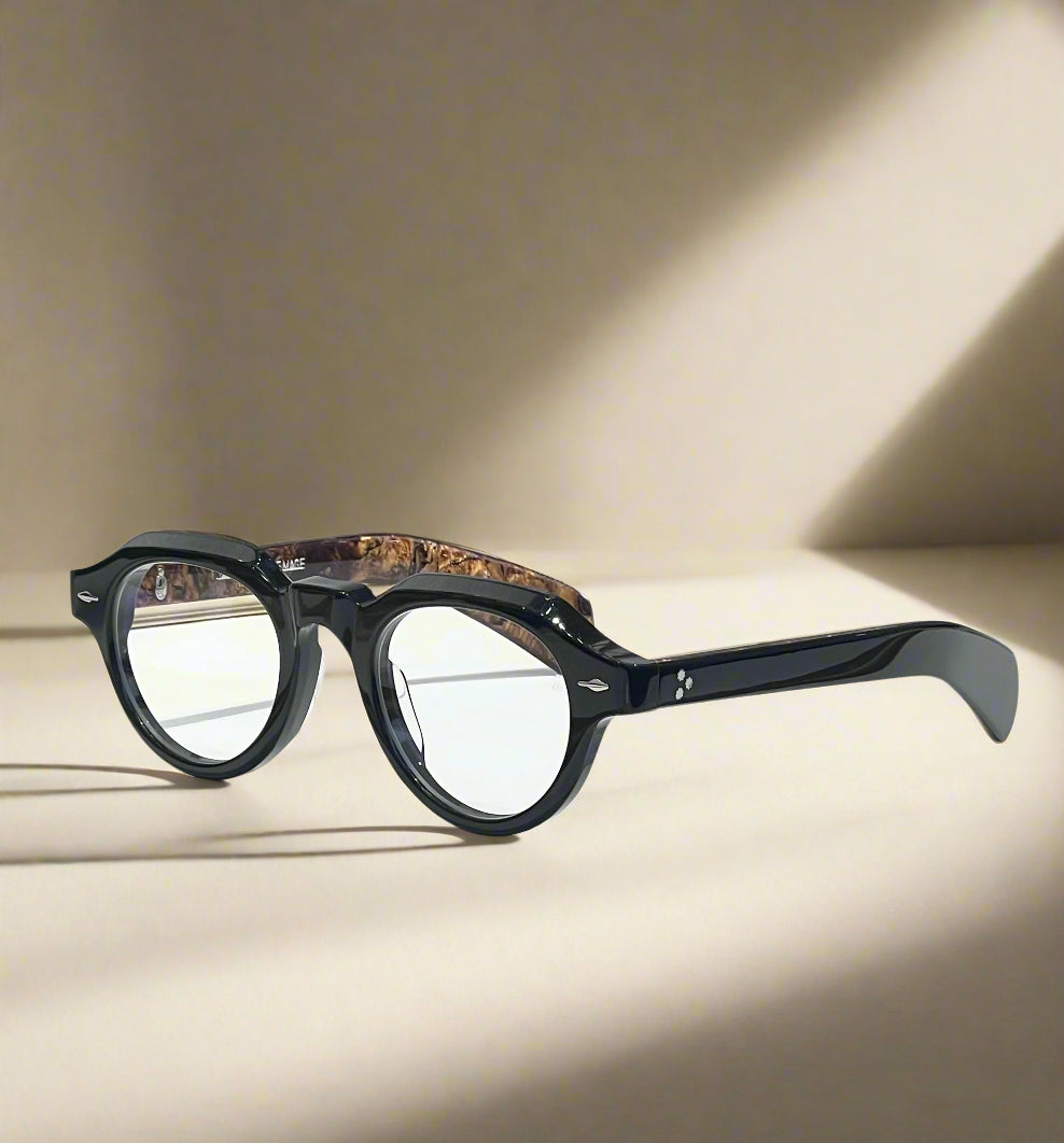 Black eyeglasses on a white surface with a branded box in the background