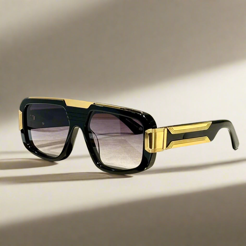 Black and gold sunglasses on a wooden surface with 'ABALMAY' branding.