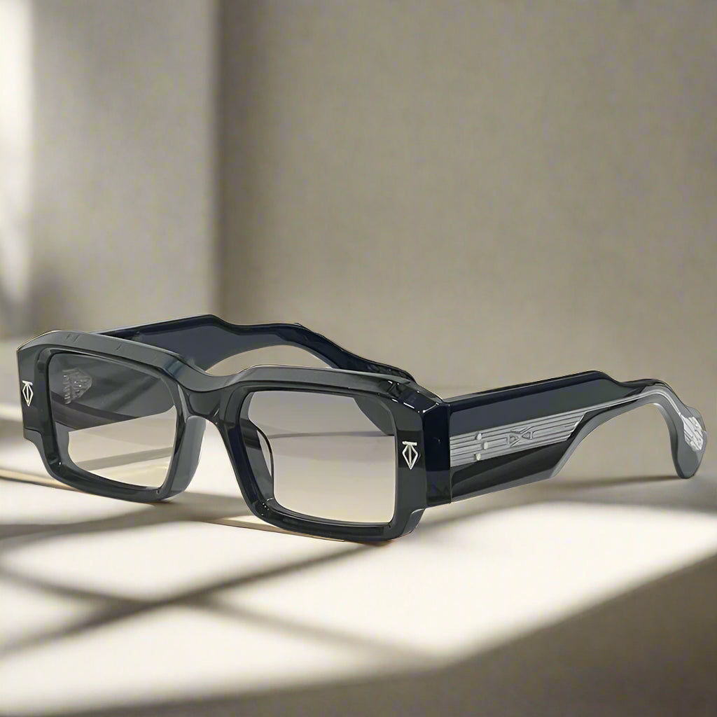 Black rectangular sunglasses on a white surface with a blue case in the background