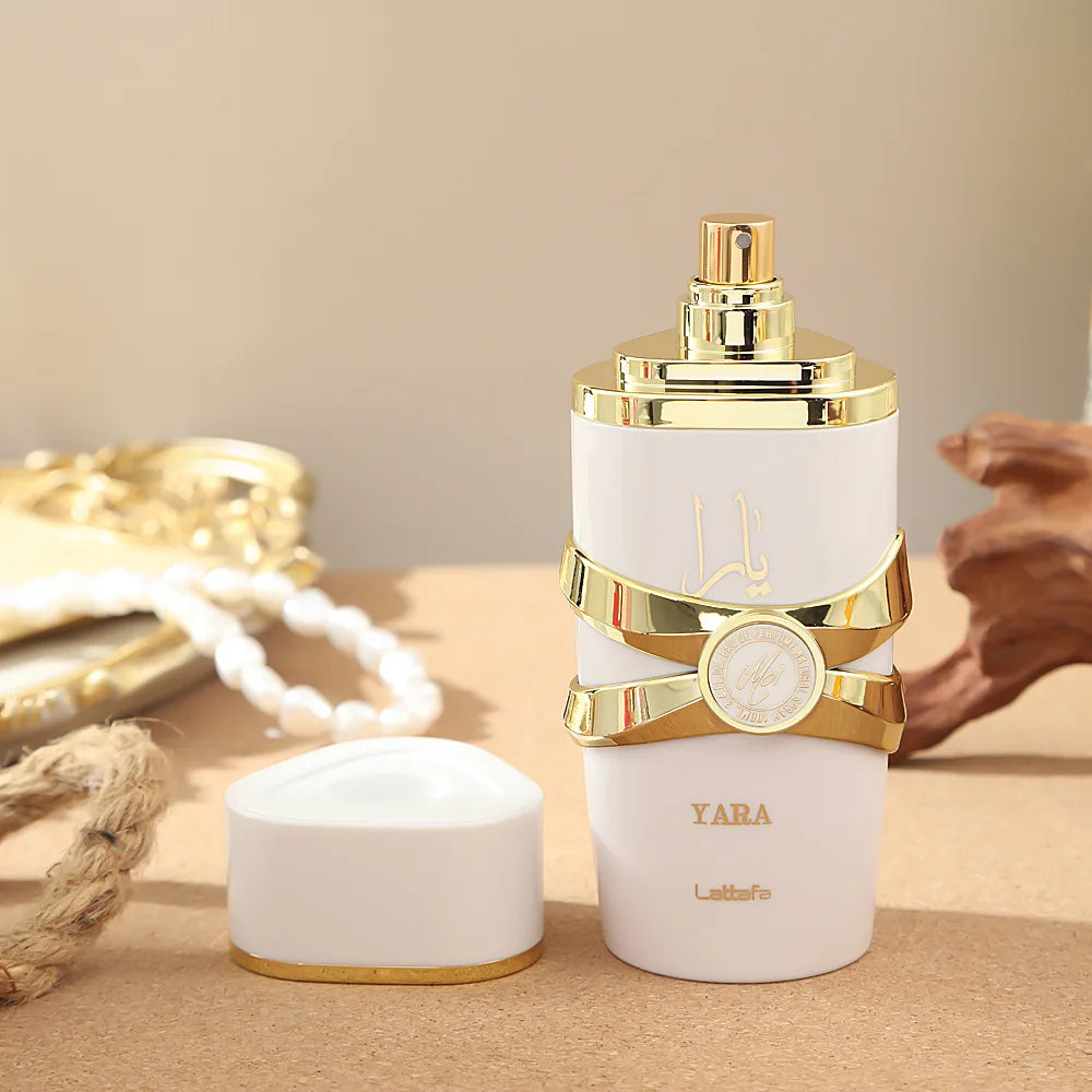 White and gold perfume bottle with 'Yara' branding on a beige background