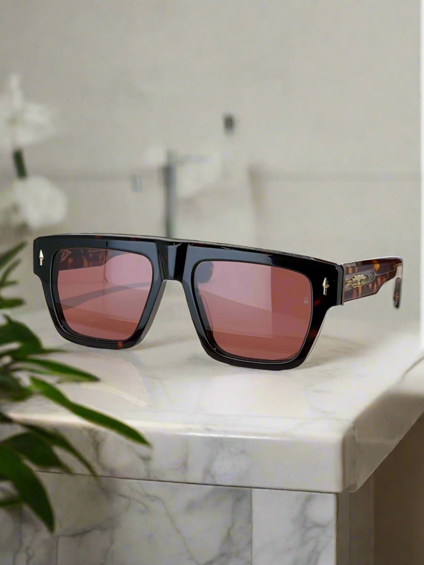Sunglasses with a brown tint on a wooden stand, with a brand box in the background.
