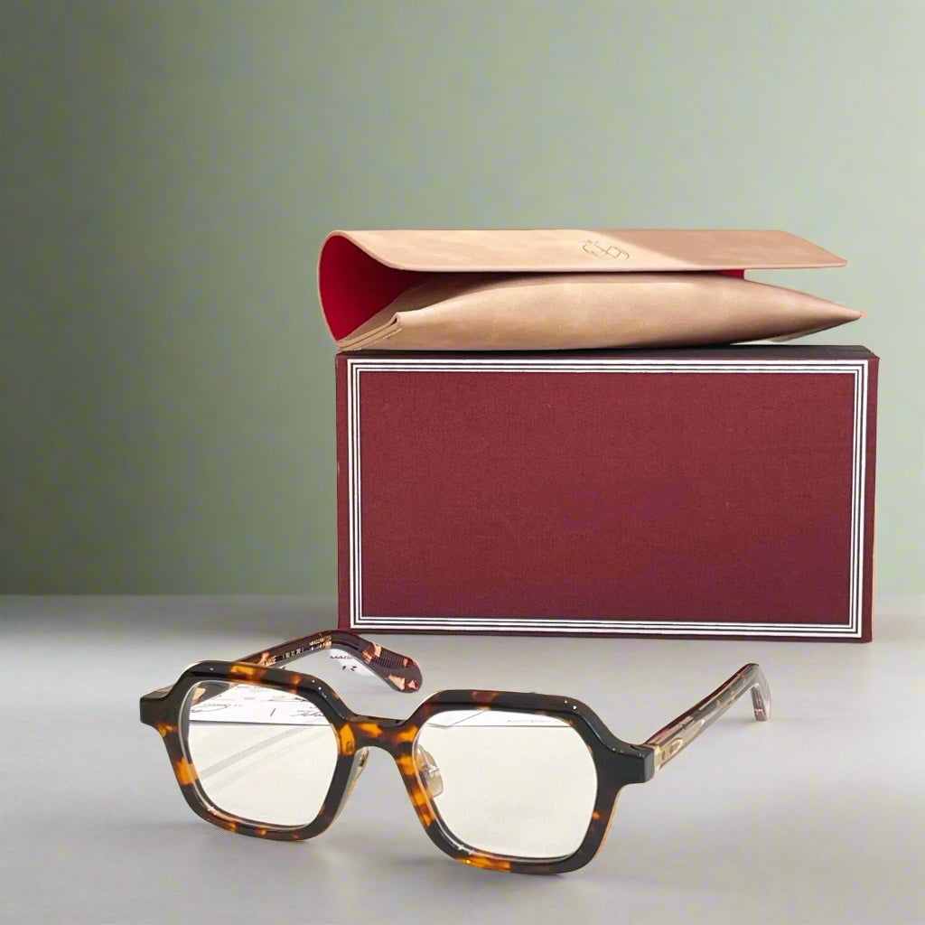 Tortoiseshell glasses with a branded box on a light surface