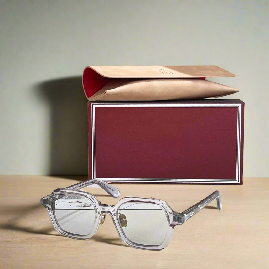 Clear eyeglasses with a red and gold box on a white surface