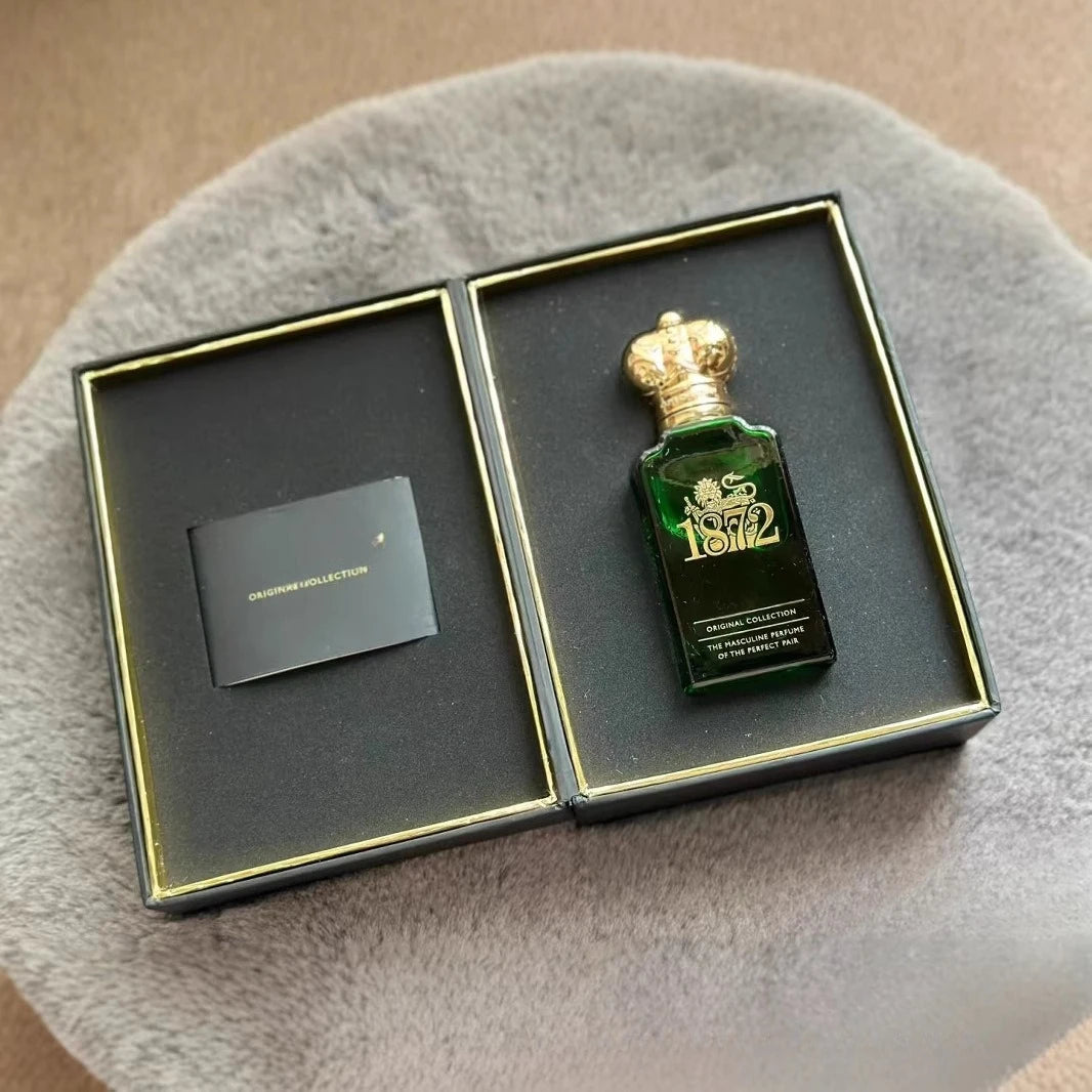 Green perfume bottle with gold cap in a black box on a gray surface