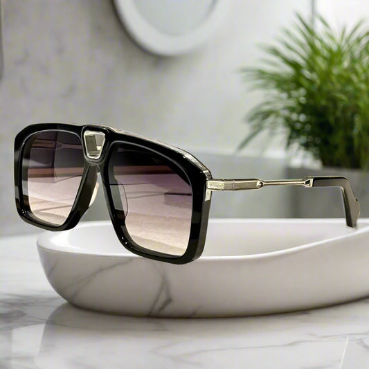 Black sunglasses with gold accents on a wooden surface