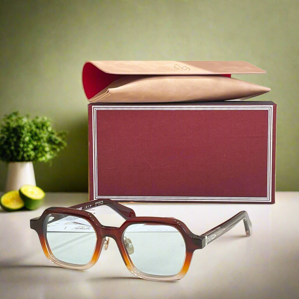 Brown eyeglasses with a red and gold box on a beige background