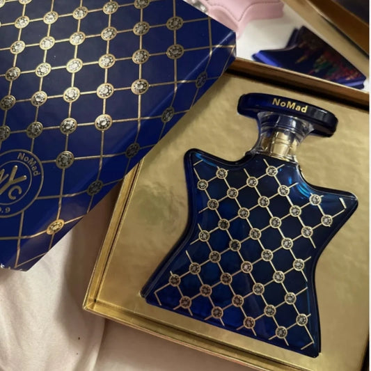 Blue perfume bottle with diamond pattern on a gold surface, next to a blue box with gold accents.