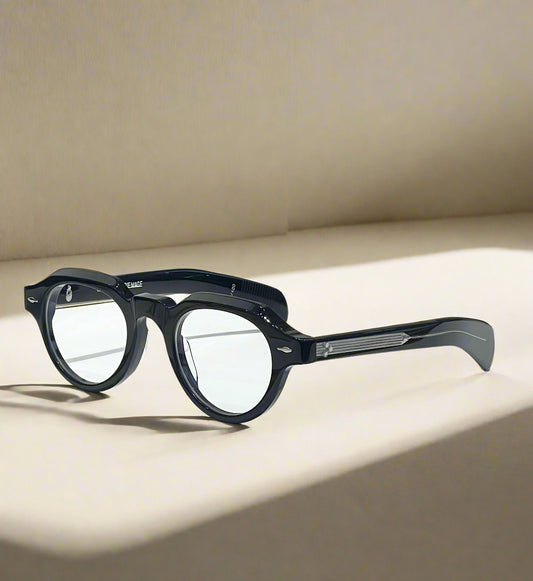Black eyeglasses on a white surface with a branded box in the background