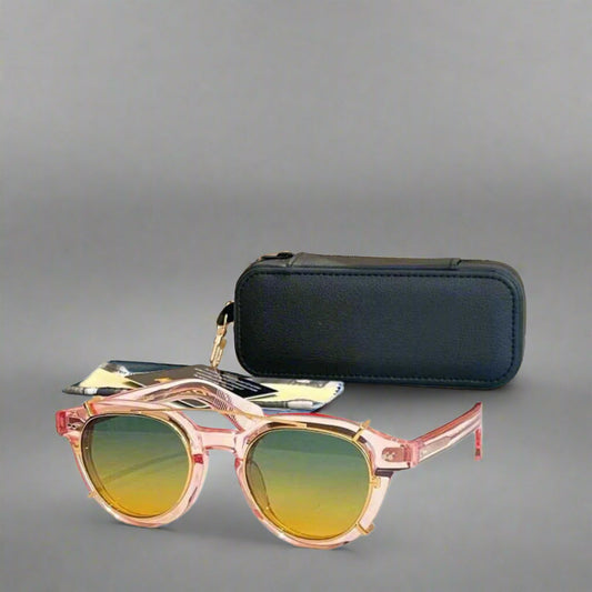 Sunglasses with pink frame and yellow gradient lenses on a white surface with a beige background
